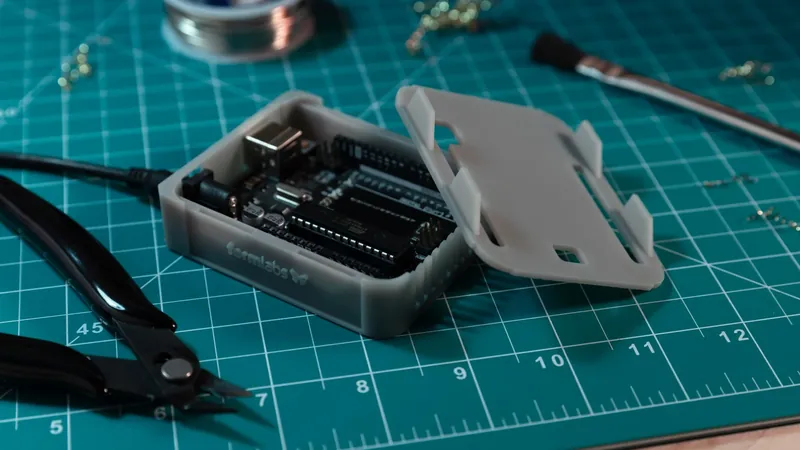 Сірий надрукований корпус для Arduino з платою всередині та кришкою поруч